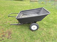 side view of black plastic lawn tractor wagon on grass