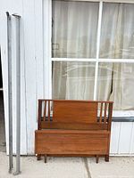 Headboard, footboard, and two metal side rails leaning against exterior wall