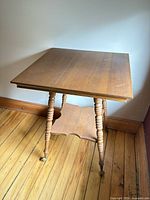 Full view of square wooden parlour table showing legs and lower shelf
