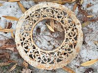 Front view of circular ornate cast iron grate with rust