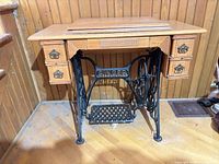 Full view of Singer treadle sewing machine cabinet closed, showing drawers and cast-iron base