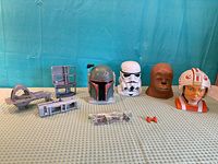 Wide view of all items including four character heads, two grey base sections, bag of accessories and orange piece
