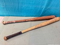 Two wooden baseball bats side by side on fabric