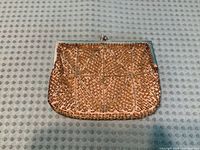 Front view of gold beaded clutch showing geometric bead pattern and metal frame