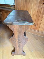 Side view of wooden side table showing magazine rack shelf and carved side profile