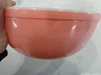 Side profile of pink bowl showing exterior color and wear