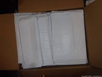 Open box showing stacked white bubble mailers