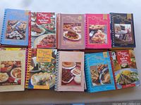 Top view of ten Company’s Coming cookbooks showing titles and coil bindings