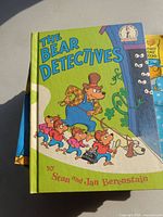 Front cover of The Bear Detectives hardcover on top of stack