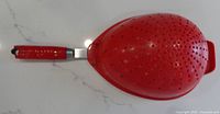 Top view of red plastic perforated strainer showing overall design and handle