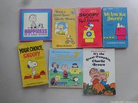 Front view of seven Peanuts paperback comic books arranged on surface