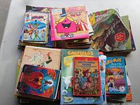 Two tall stacks of assorted children's books and comics on tabletop