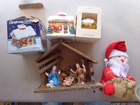 Group shot of ceramic houses with boxes, nativity stable with figures, plush Santa