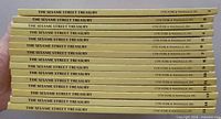 Side view of all 15 books stacked showing uniform yellow spines and volume numbers
