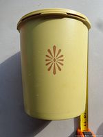 Front view of cream Tupperware container showing starburst graphic and height reference