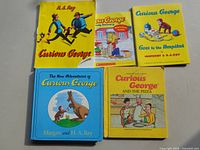 Five larger books laid flat showing titles and cover art