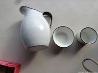 Side view of white enamel jug and two cups