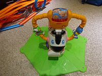 Top view showing handlebar module, attached toys, and zebra face on green base