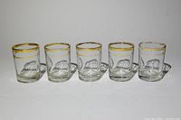 Five gold rim shot glasses front view
