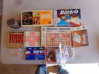Overview of multiple boxed games, bagged pieces and jar on table
