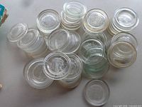 Stacked group of clear glass canning lids showing crown embossing and varying clarity