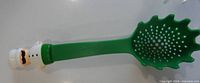 Full view of green spaghetti spoon showing perforated bowl and chef handle