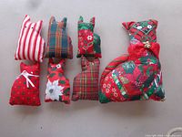 Front view of six stuffed fabric cat decorations displaying sizes and various holiday prints