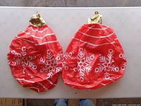 Two deflated red inflatable Christmas ornaments with snowflake design and gold caps
