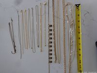 Gold-tone necklaces and bracelets laid beside measuring tape