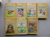 Seven Laura Ingalls Wilder Little House series paperbacks laid out in two rows showing front covers and condition