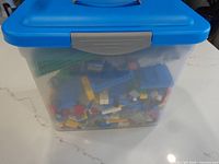 Storage bucket with blue lid showing mixed Lego pieces inside