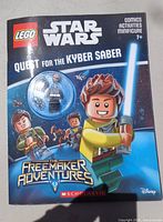 Front cover showing sealed LEGO Star Wars Quest for the Kyber Saber book and blister-packed minifigure