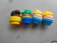 Four Little Tikes plastic people figures lined up showing hairstyles and colors