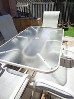 glass patio table with four chairs visible