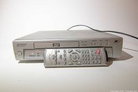 Front view of Lenoxx Sound DVD-2002 DVD player with remote placed on disc tray