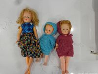 Three dolls lying side by side showing full outfits and size comparison