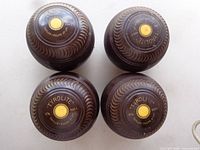 Top view of four brown Tyrolite lawn bowls showing centre disks and grip patterns