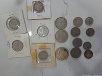 Overview of four coins in cardboard flips and loose coins on right
