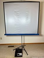 Screen fully extended on tripod with projector at base