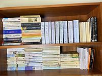 Overall view of two shelves holding approximately 70 paperback books, showing Poldark series, Catrin Collier titles and assorted classics