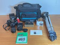 Group shot showing all items: Ricoh camera with lens, extra lens, flash, Kodak camera and box, tripod, bag, manuals, light meter, binocular case, cleaning fluid
