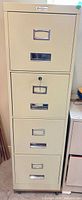 Full view of closed 4-drawer beige metal filing cabinet showing Commodore badge