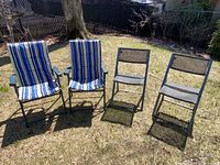 Full set of four folding chairs outdoors; two cushioned striped chairs and two gray mesh chairs