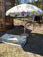 Full view of opened floral patio umbrella with folded canopy nearby