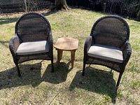 Two wicker chairs and wood side table displayed outdoors