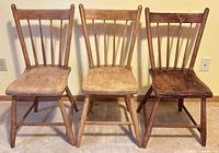 Front view of three spindle-back wooden chairs