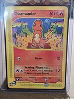 Front of Charmander card in sleeve and toploader showing condition and details