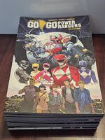 Front cover of top book "Go Go Power Rangers Volume One" and top of stack showing multiple books