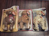Front view of three sealed bears in blister packs on table