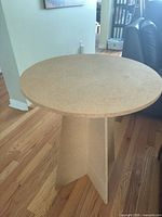 Full view of round unfinished MDF side table on wood floor